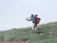 photographer lugging large camera rig on a tripod